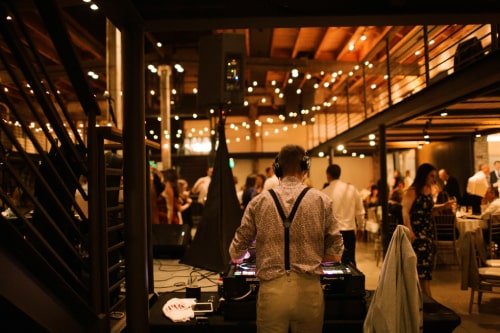 Crowd dancing in rustic barn with string lighting