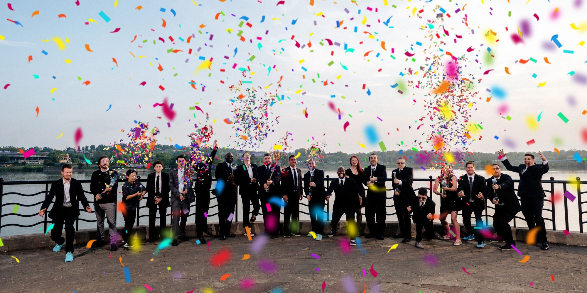 Klock Entertainment team lined up for a group photo with colorful confetti canons shooting in the air.