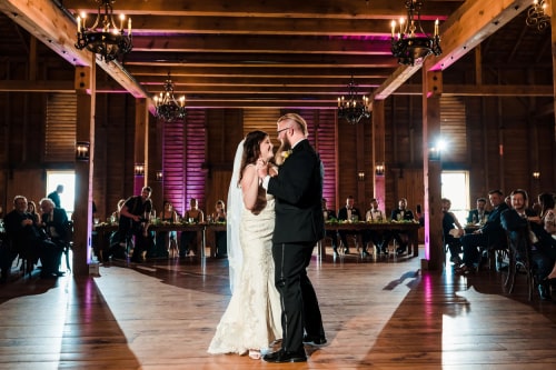 Newly weds sharing their first dance on an empty dance floor with white and purple spotlights